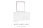 White rectangular bedroom mirror on top of a dresser with six drawer fronts