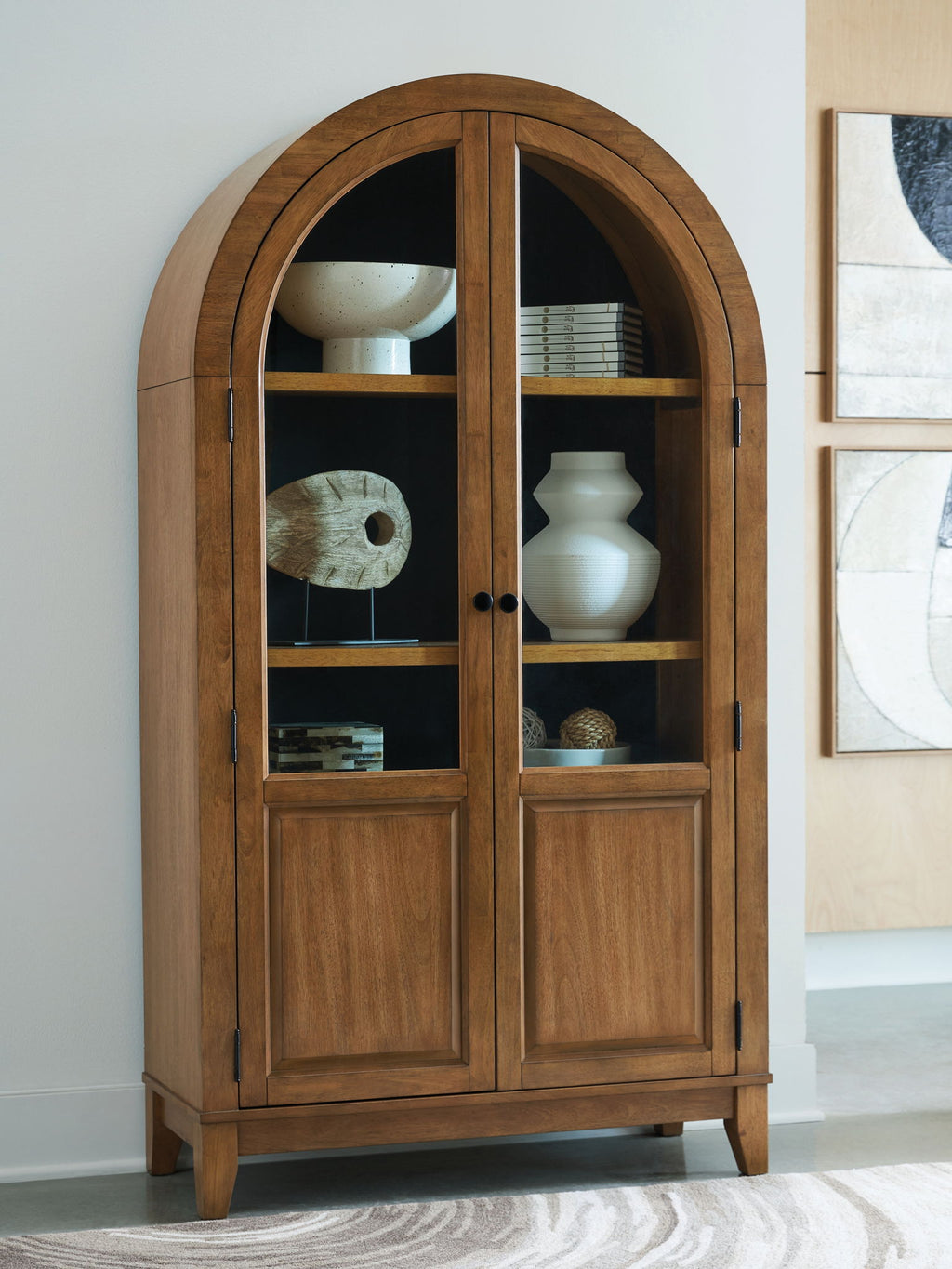 Light brown arched accent cabinet with double doors and glass panels, visible shelves