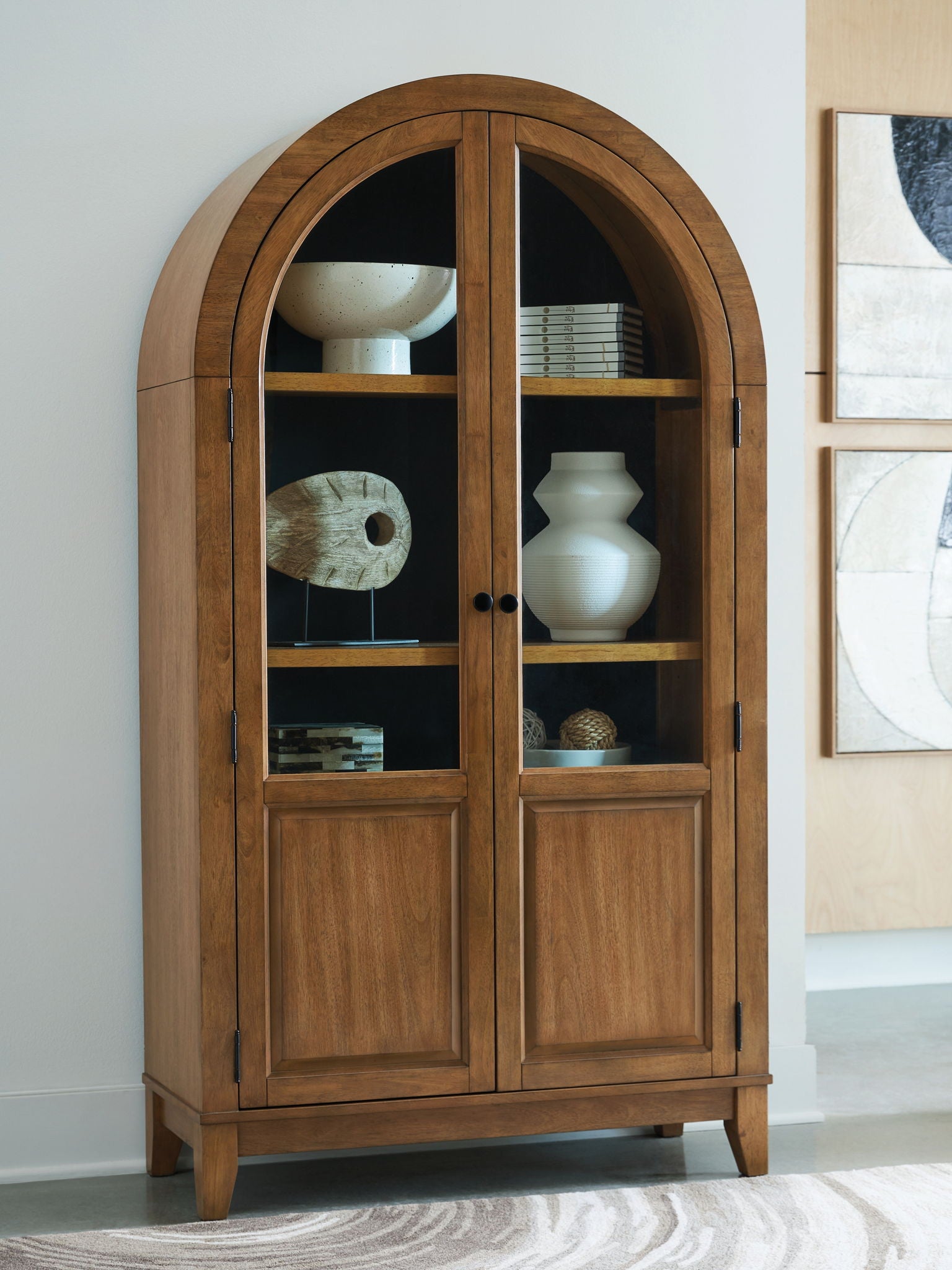 Light brown arched accent cabinet with double doors and glass panels, visible shelves