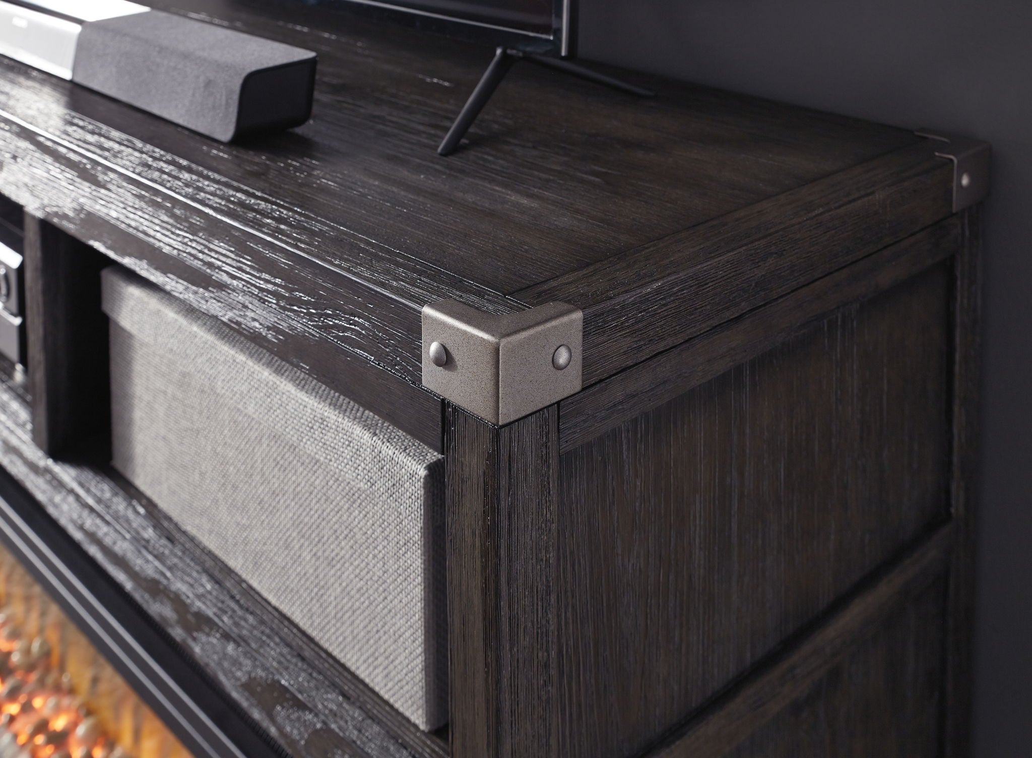 Gray TV stand corner detail with metal brackets and wood grain top
