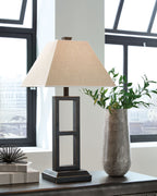 Black metal table lamp with tan fabric shade, glass window panels, on desk