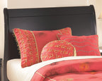 Black youth sleigh headboard with arched top above bed pillows