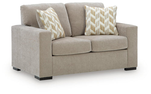 Light beige upholstered loveseat with two patterned accent pillows and square arms