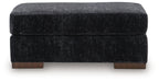 Black upholstered ottoman with stitched top seam and dark wooden feet