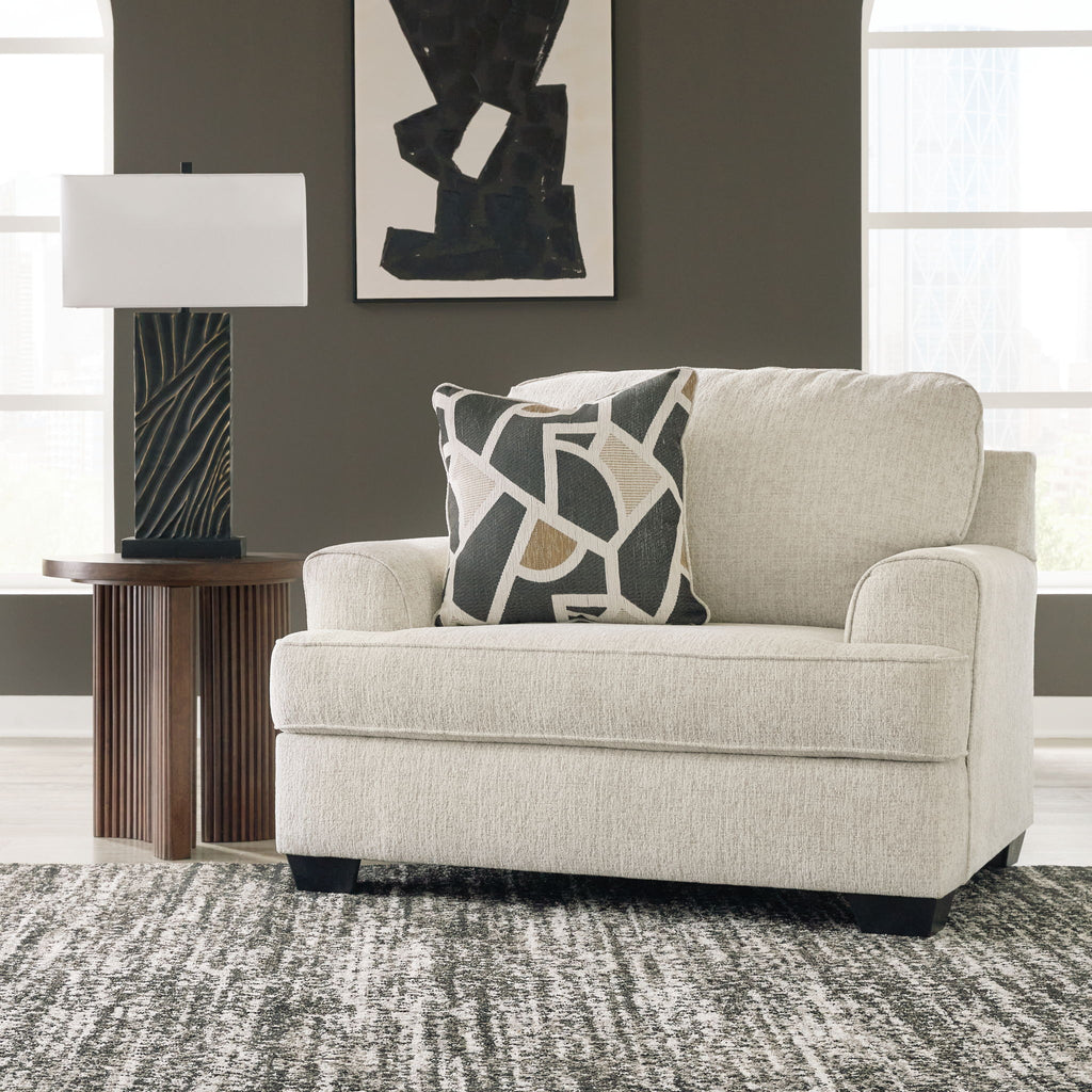 Beige upholstered living room chair with patterned throw pillow and square ottoman