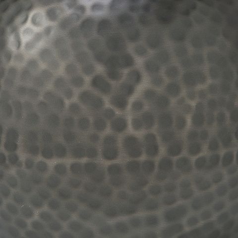 Close-up of dark gray hammered ceramic vase texture with dimpled surface