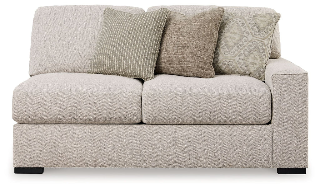 Sand-colored upholstered loveseat with rounded arms and three throw pillows