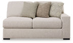 Sand-colored upholstered loveseat with rounded arms and three throw pillows