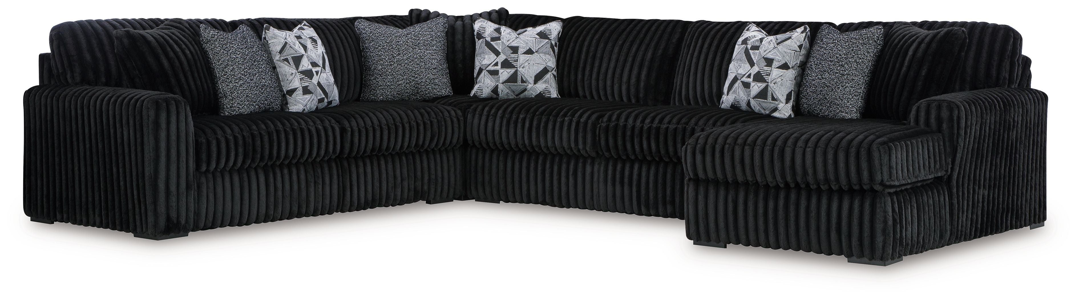Black sectional sofa with chaise corner, ribbed upholstery, and four patterned throw pillows