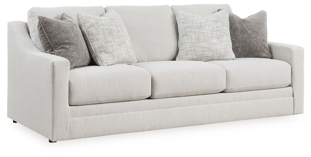 Chalk-colored sofa with three seat cushions and gray accent pillows