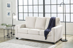 Light beige sofa with white cushions and dark blue throw blanket