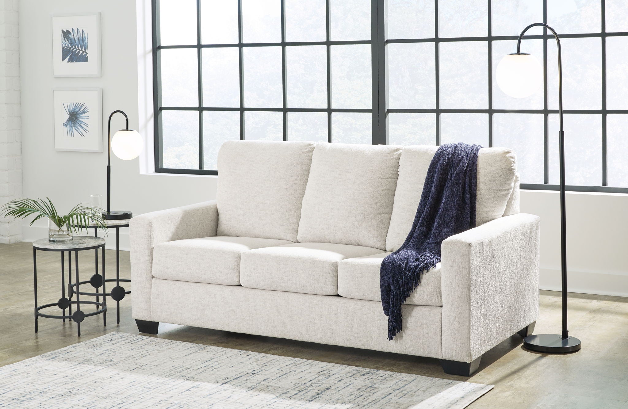 Light beige sofa with white cushions and dark blue throw blanket