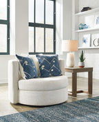 Ivory swivel accent chair with navy patterned pillows, rounded seat and arms