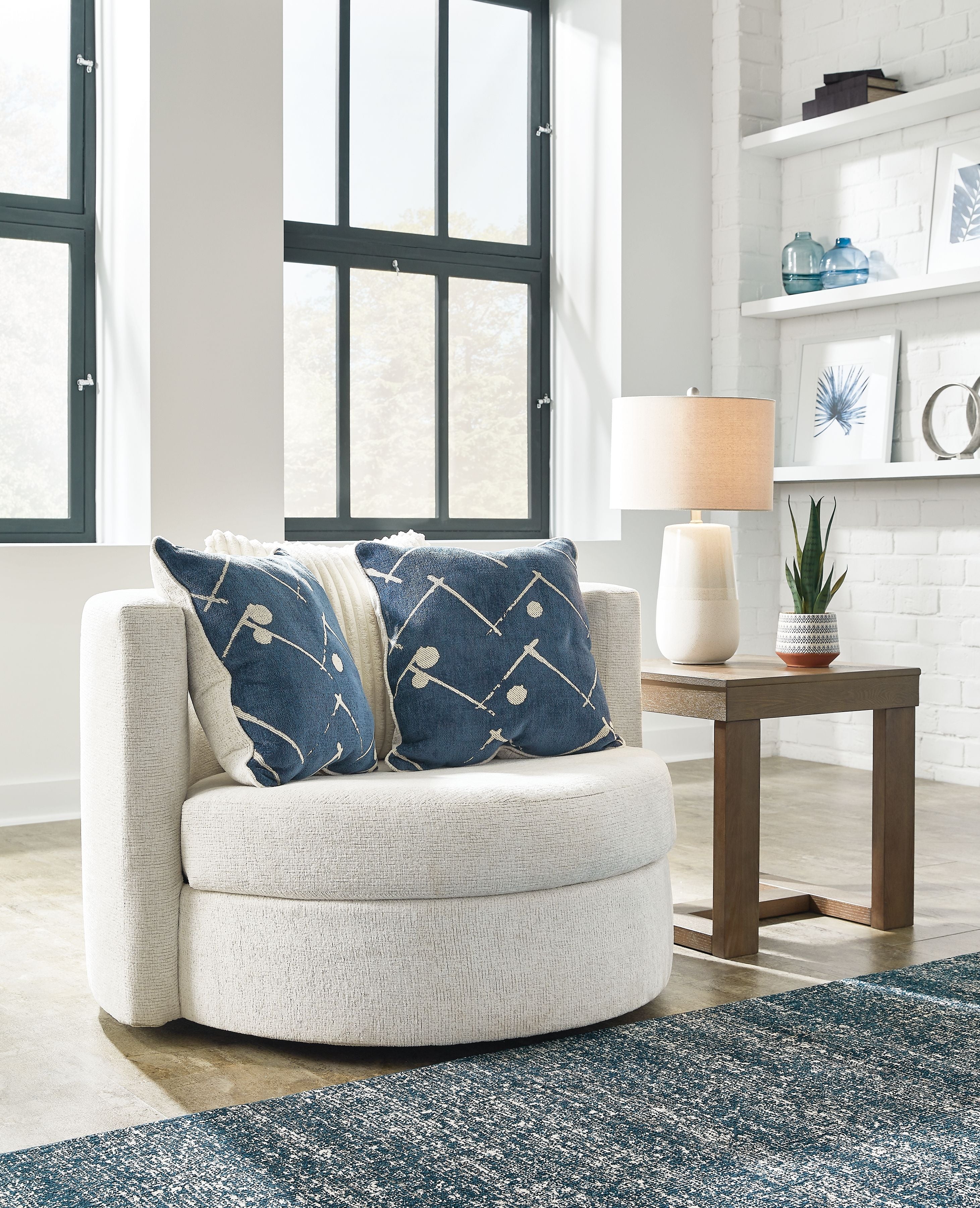 Ivory swivel accent chair with navy patterned pillows, rounded seat and arms