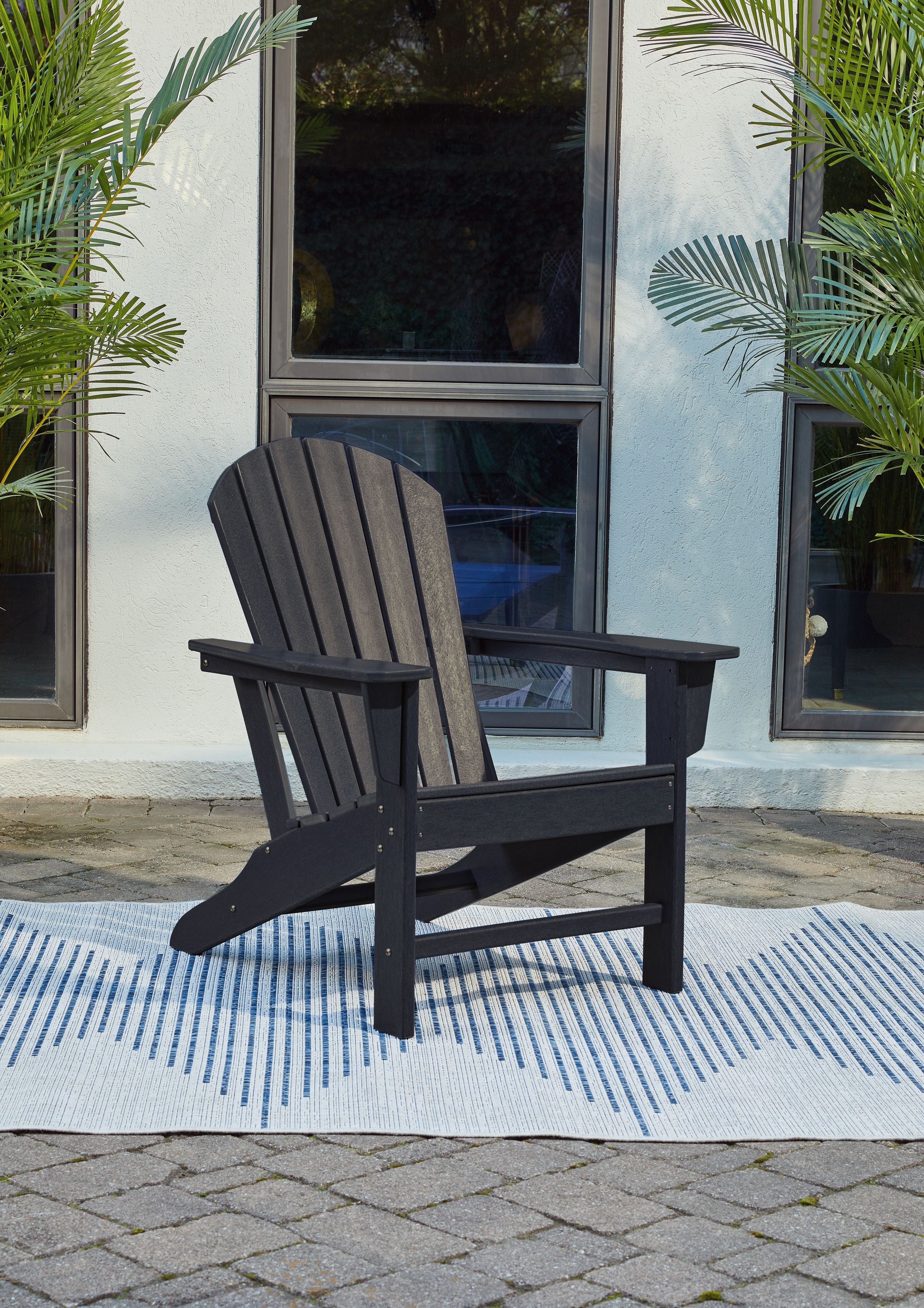 Outdoor Adirondack chair in dark blue with slatted back, armrests, and side supports.