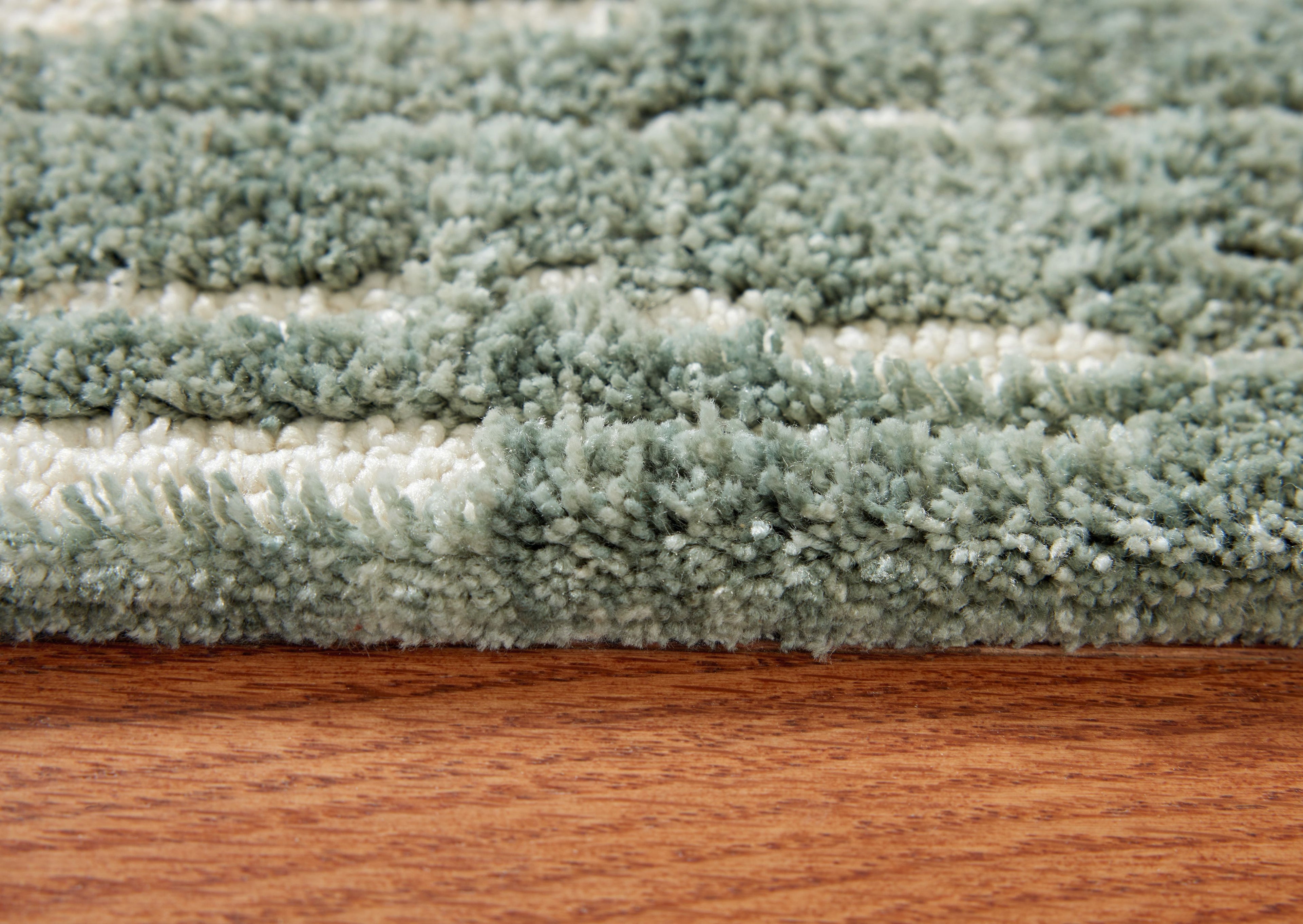 Light blue shag area rug with dense textured pile, close-up edge view