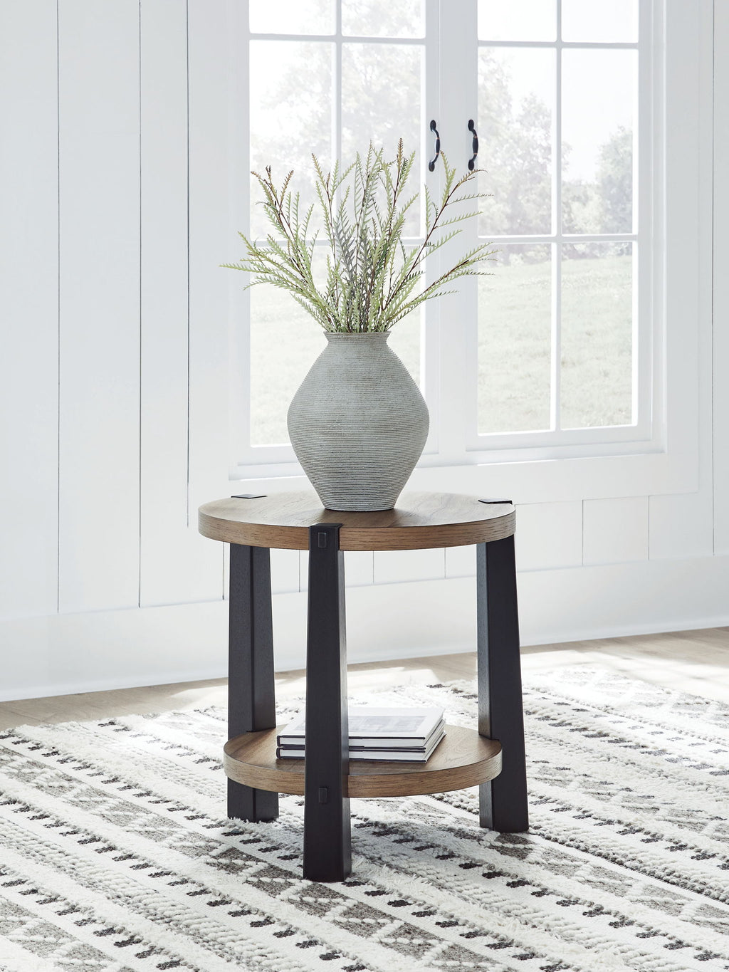 Round two-tier end table with light wood top and dark legs, placed in a living room.
