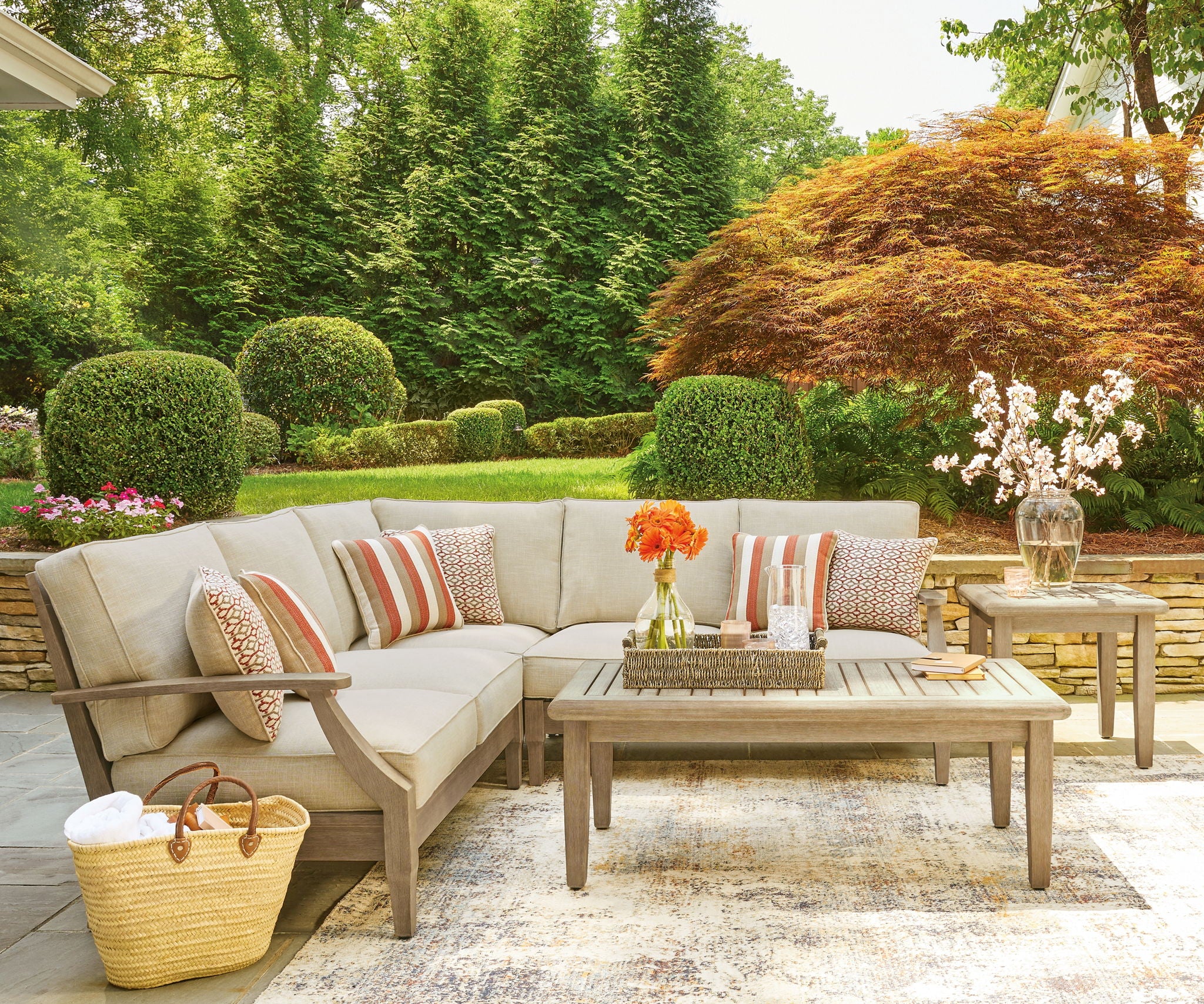 Beige outdoor sectional sofa with striped throw pillows and patterned accent cushions
