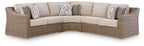 Beige outdoor sectional sofa with cushioned seats and two throw pillows