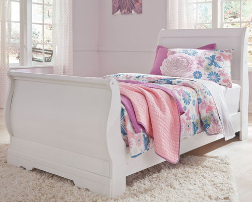 White sleigh bed with tall headboard and open side, dressed in pink and blue floral sheets.