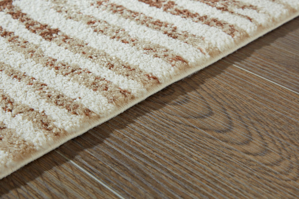 Area rug detail: cream pile with rust patterned bands along the edge