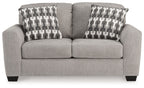 Gray flannel loveseat with two patterned pillows and cushioned arms
