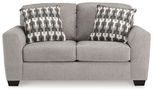 Gray flannel loveseat with two patterned pillows and cushioned arms