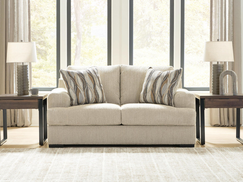 Beige loveseat with two seat cushions and three back pillows with striped patterns