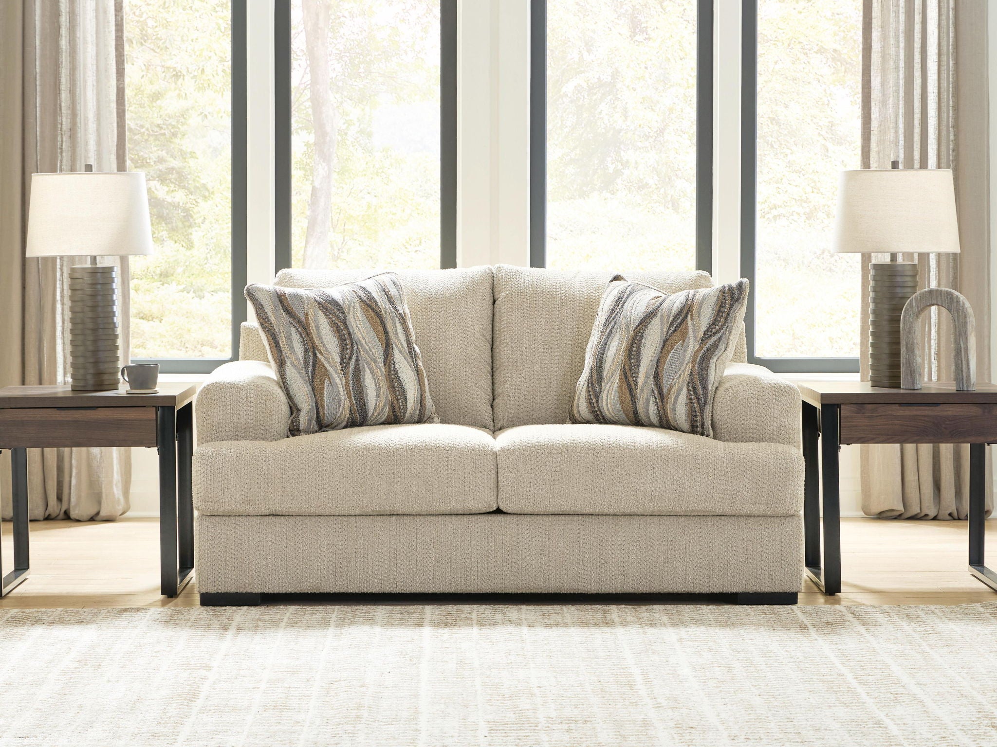 Beige loveseat with two seat cushions and three back pillows with striped patterns