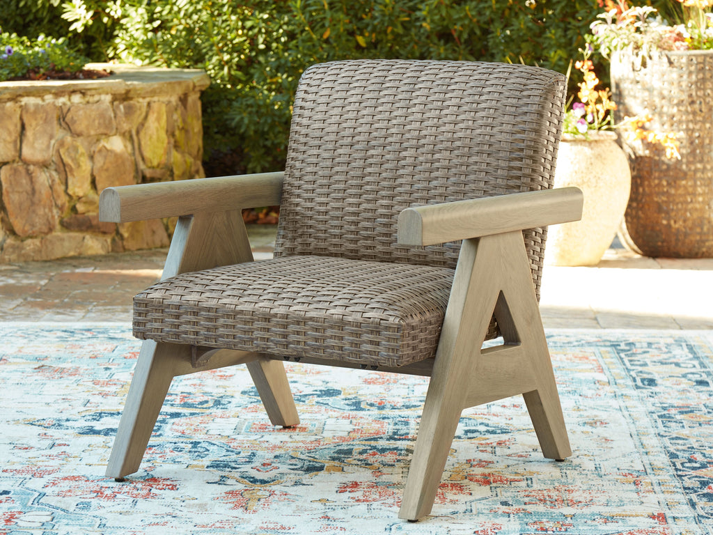 Beige woven rocking lounge chair with wooden armrests and visible rocker base