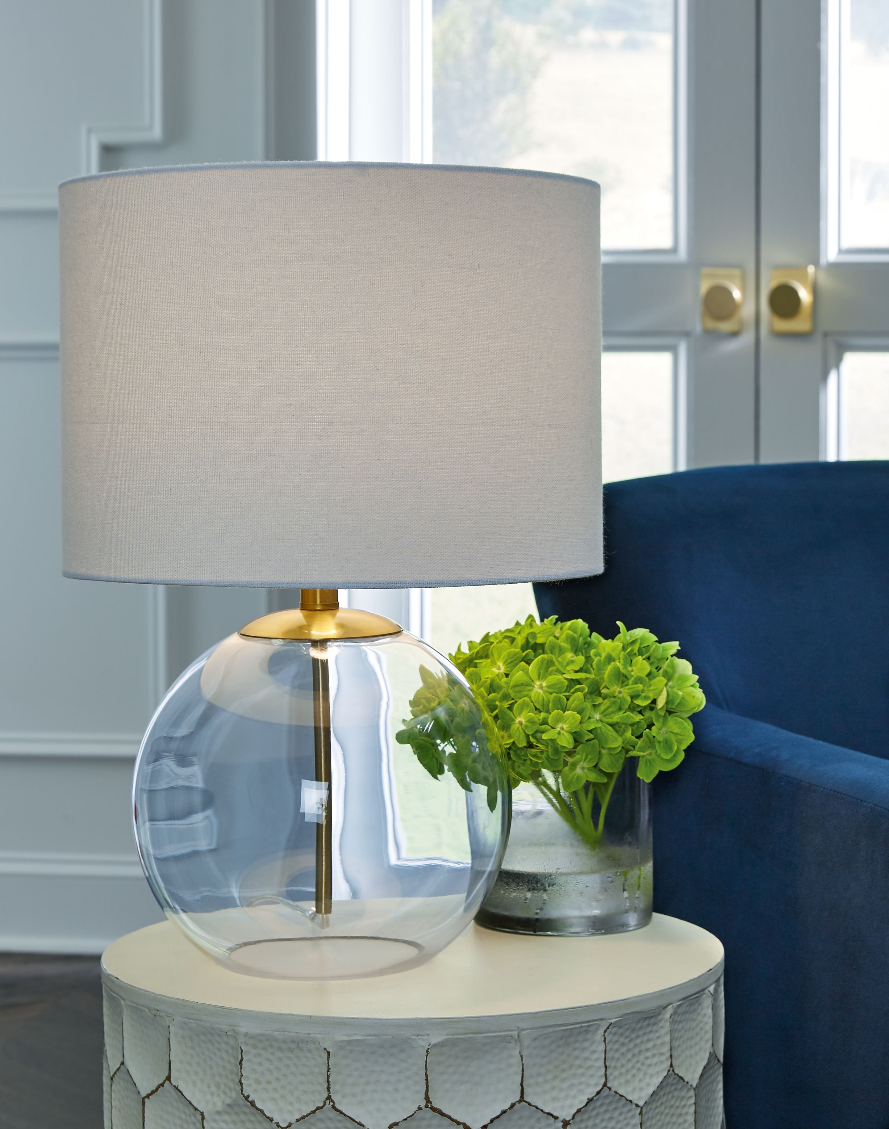 Glass table lamp with beige-white fabric shade and clear glass globe on brass base