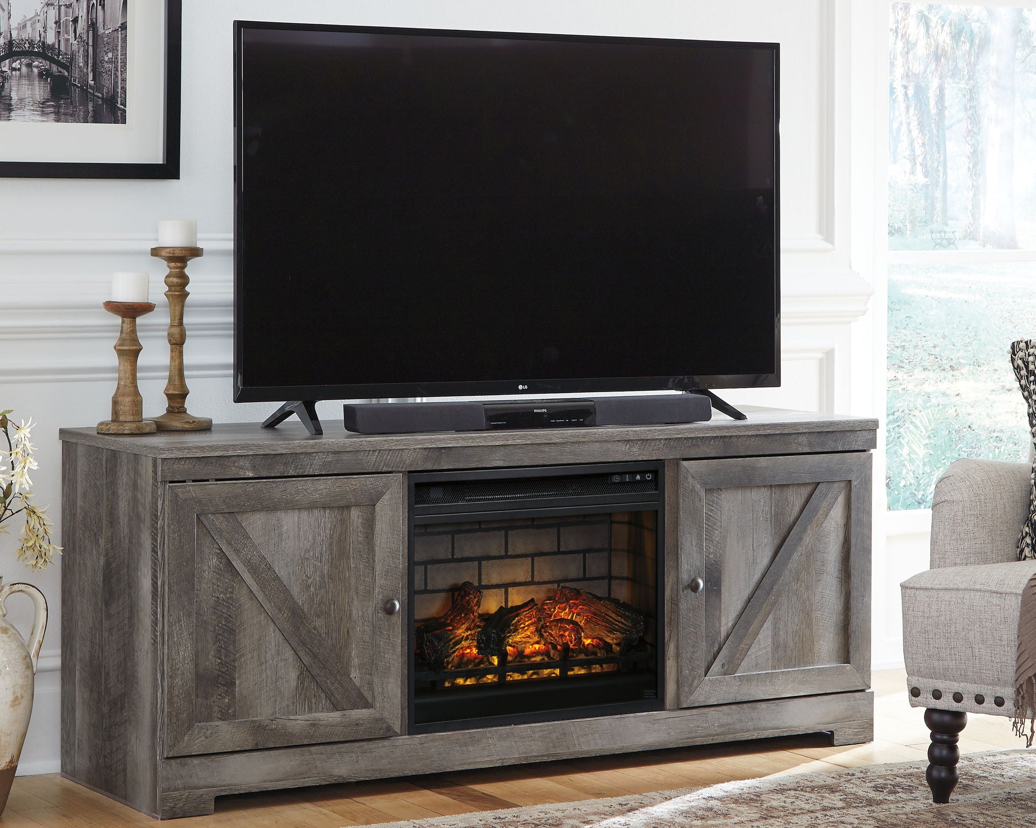 Gray media console with TV on top and glowing fireplace insert in center cabinet