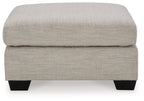 Oversized ottoman with light beige fabric, thick cushioned top and squared black legs.