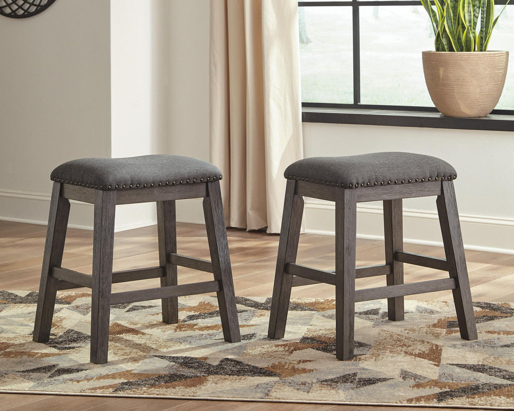 Two dark gray upholstered backless stools with button-tufted padded seats and wooden legs