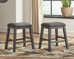 Two dark gray upholstered backless stools with button-tufted padded seats and wooden legs