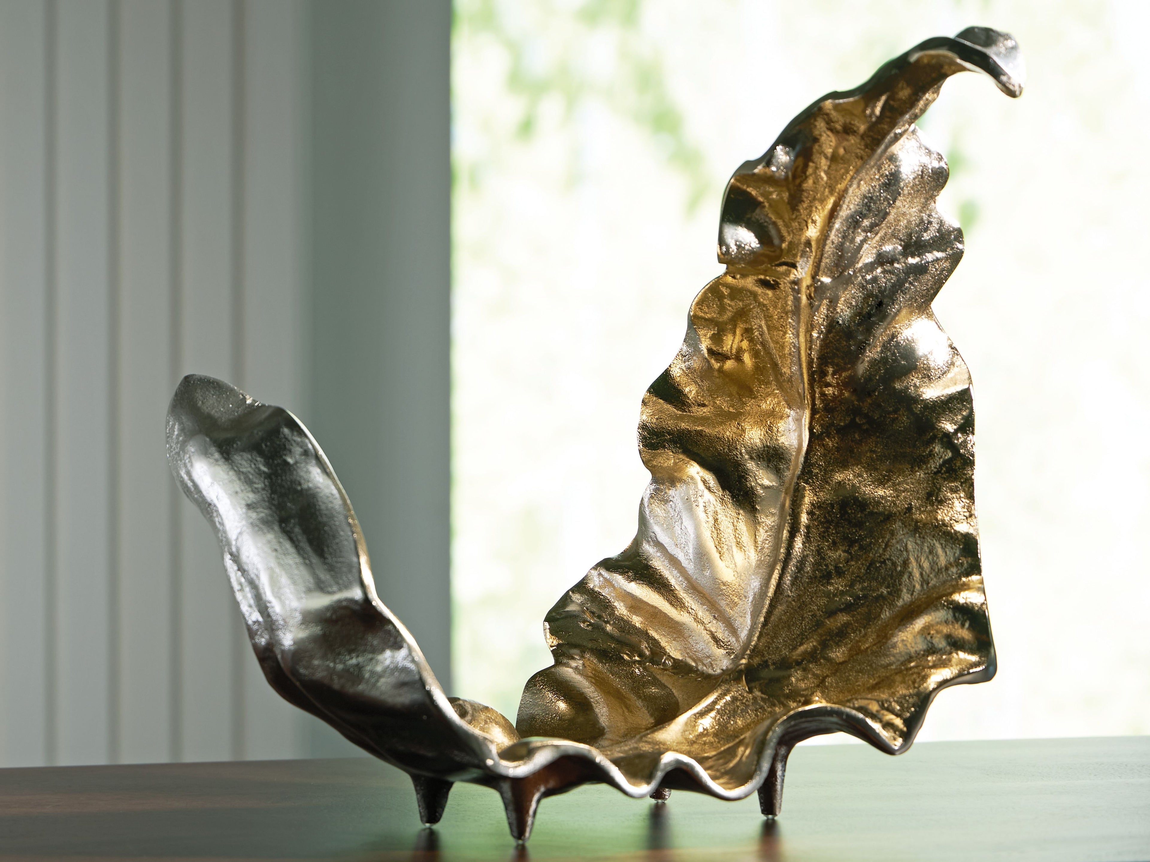 Gold and silver abstract sculpture on pedestal, winged relief form