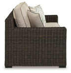 Brown wicker loveseat with beige seat cushions and two back pillows