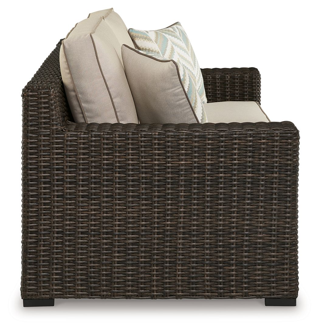Brown wicker loveseat with beige seat cushions and two back pillows