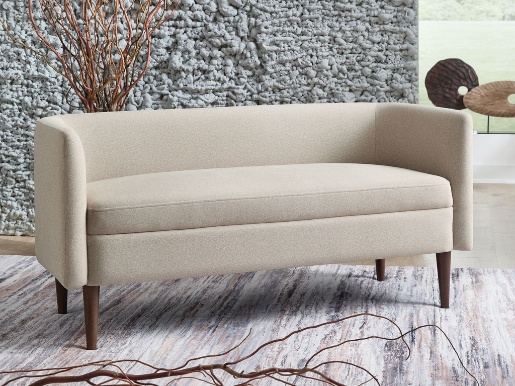 Beige upholstered accent bench with rounded back and seat, dark tapered legs