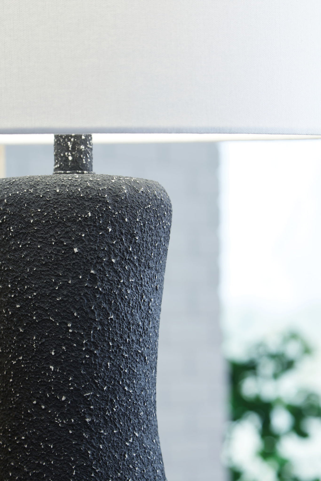 Textured black metal lamp base with speckled finish and white drum shade edge