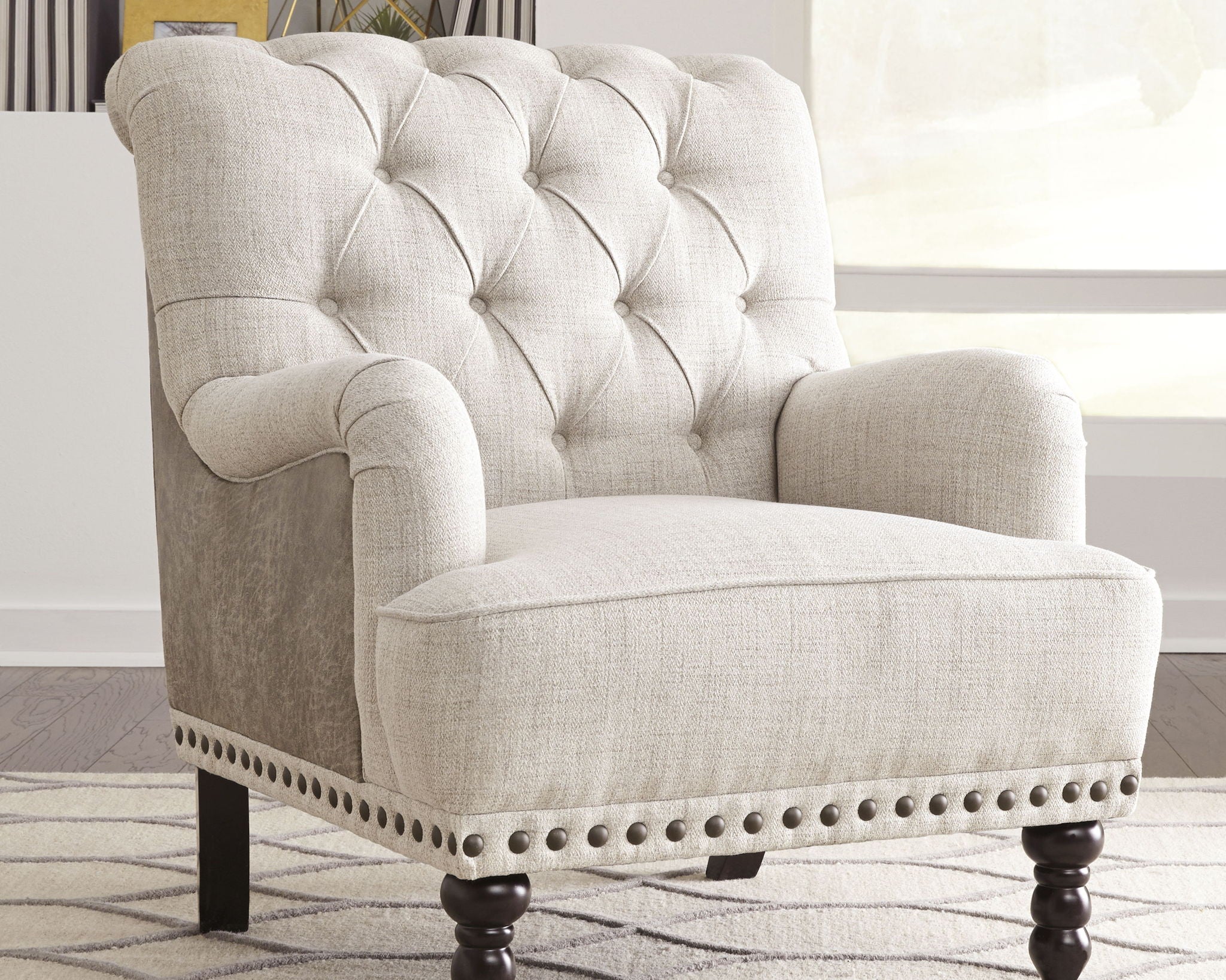 Light gray upholstered accent chair with tufted back, rolled arms, and nailhead trim