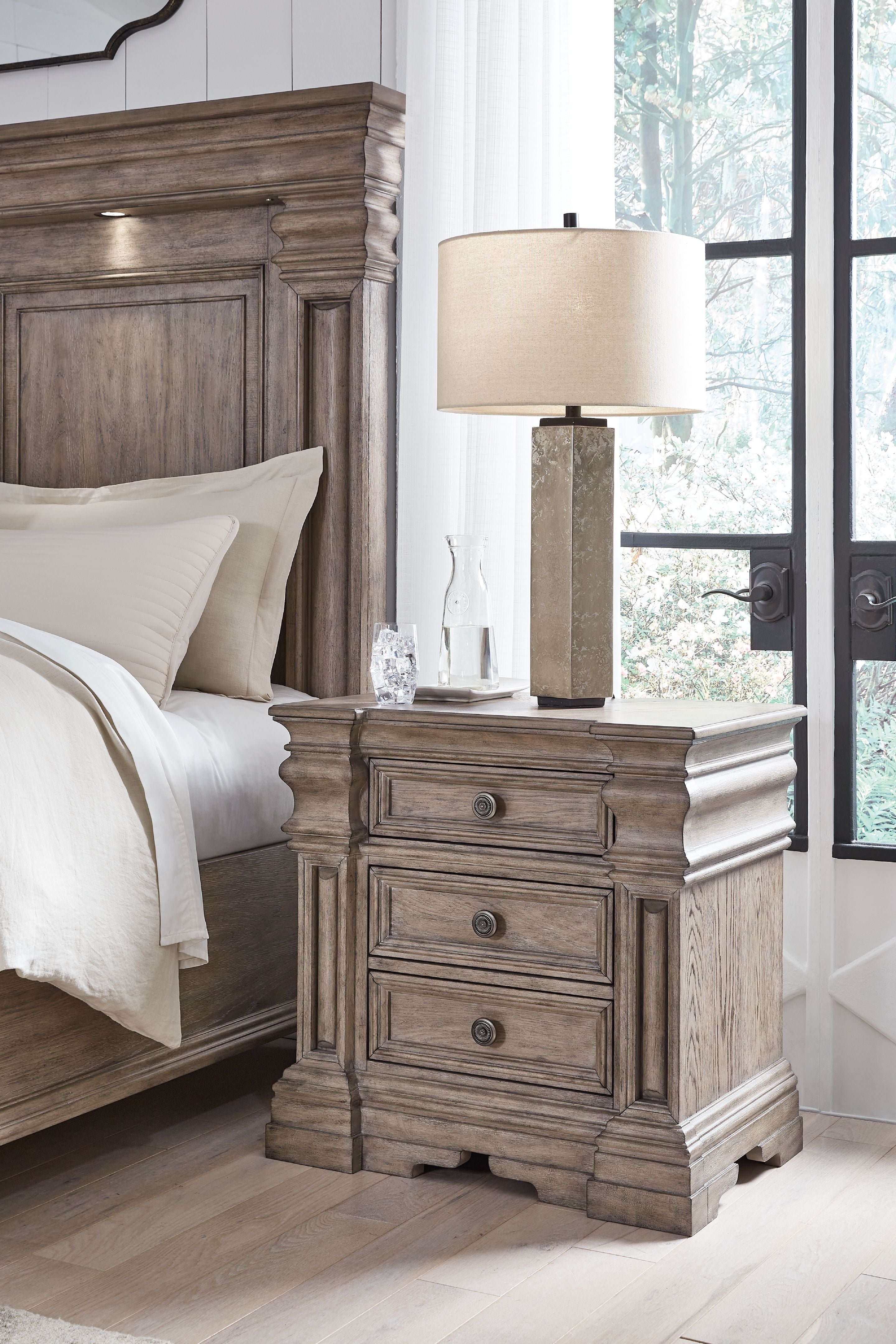 Three-drawer night stand with lamp on top, light grayish brown finish, round knobs
