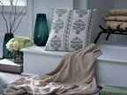 Patterned throw pillow with dark gray fabric and blue floral border on a sofa
