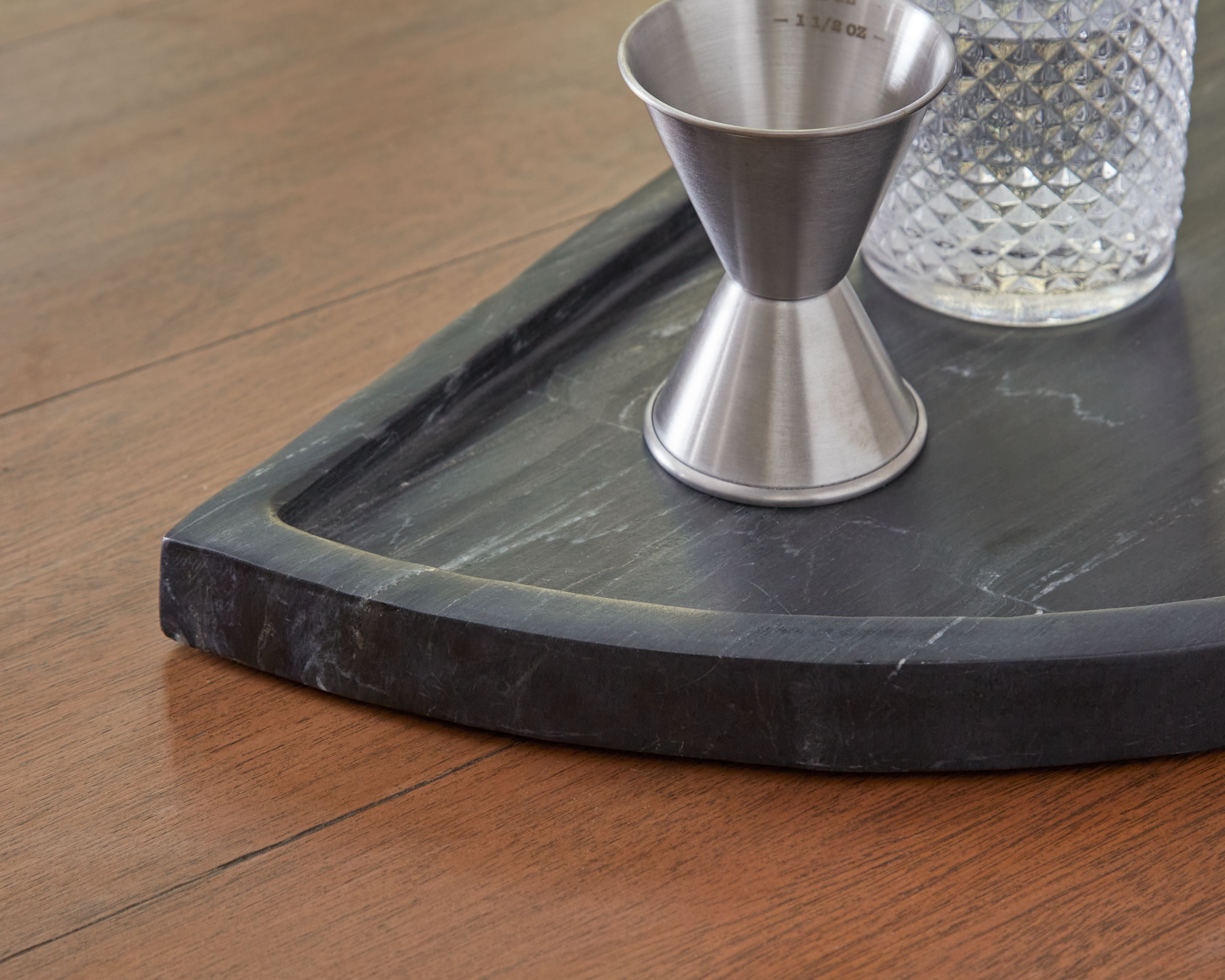 Dark stone-look corner of serving tray with shallow basin and beveled edge.
