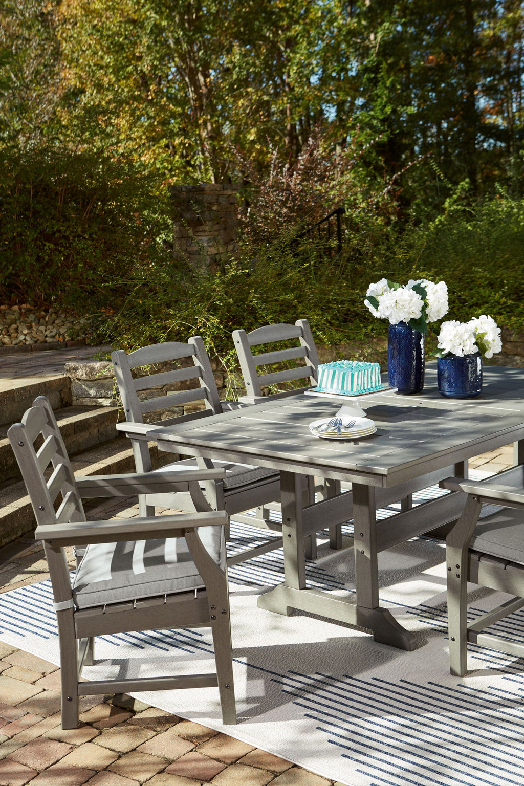 Gray outdoor dining table with four slat-back chairs in view