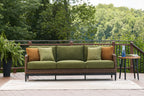 Green sofa with woven wicker frame, brown accent pillows, and patterned cushions