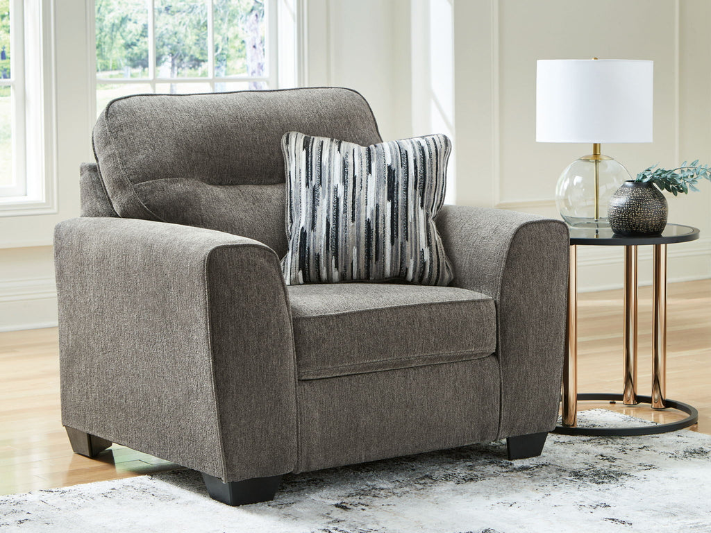 Dark gray upholstered chair and a half with striped throw pillow and rounded arms