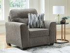 Dark gray upholstered chair and a half with striped throw pillow and rounded arms