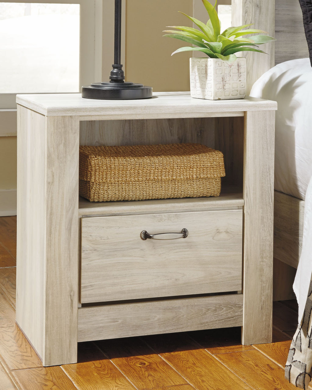 Whitewash one-drawer nightstand with open shelf and woven basket, bar drawer pull