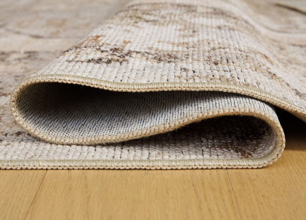 Washable rug edge close-up with light woven texture and bound rug border